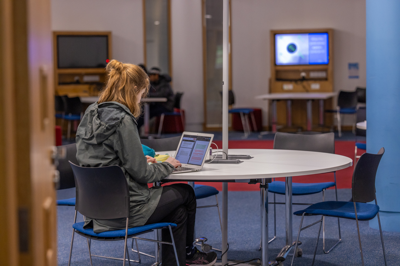 Student studying at desk in the Library at the Gateway, with screens in the background